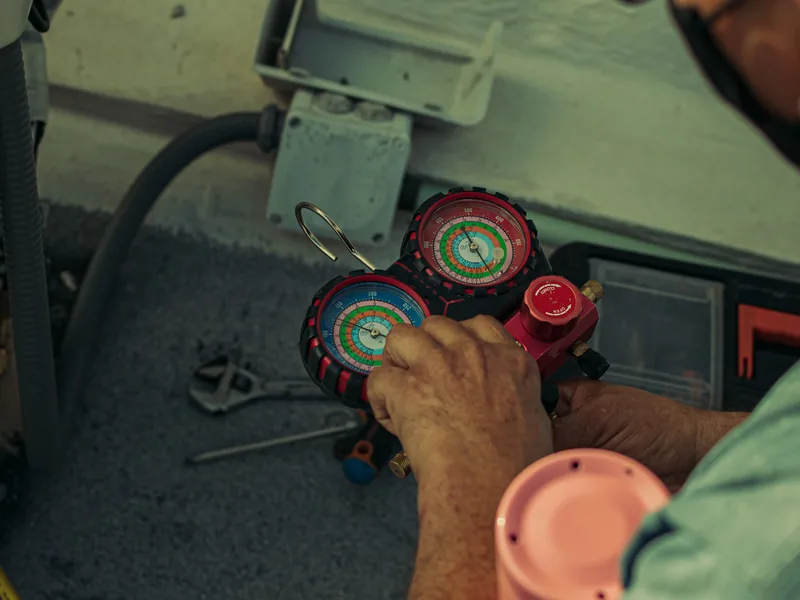Technicien en maintenance de climatisation avec manifold de mesure